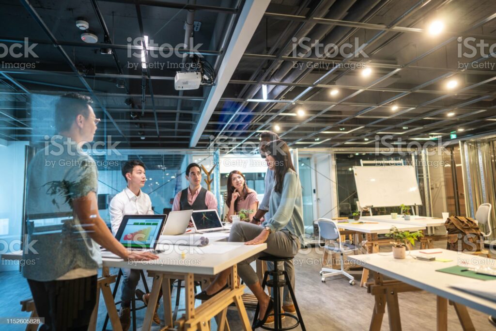 Group of young, modern people sitting on business meeting in modern coworking space and suggesting ideas for the best business strategy